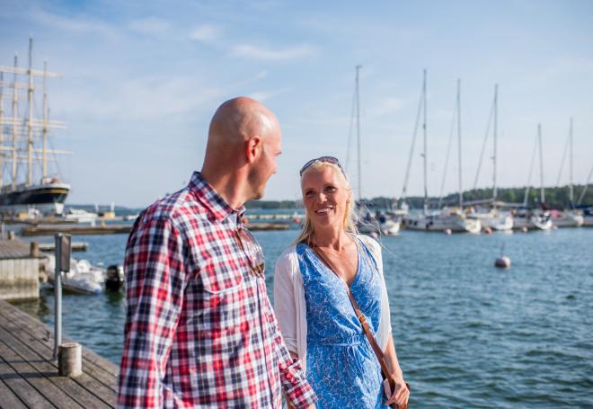 Par promenerar hand i hand vid bryggkanten i västra hamnen i Mariehamn.